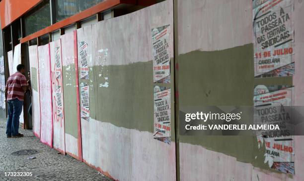 Man gets into a bank office with its doors and windows closed with boards in Rio de Janeiro, Brazil, on July 10 on the eve of a nationwide day of...