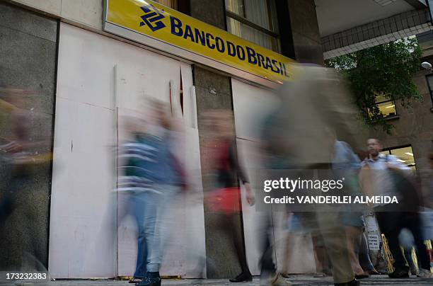 Pedestrians pass by a Banco de Brasil bank branch with its door and windows closed with boards in Rio de Janeiro, Brazil, on July 10 on the eve of a...