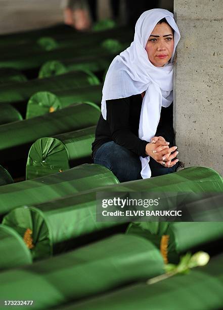 Bosnian Muslim woman, survivor of Srebrenica 1995 massacre, mourns near body caskets of her relatives, layed out in a factory hangar, near memorial...