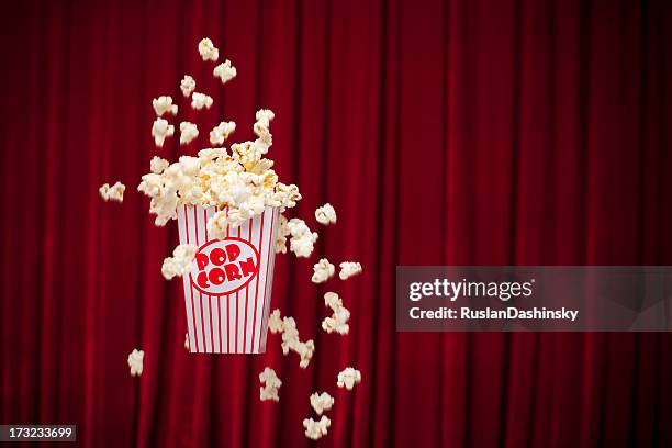 a container of popcorn spilled on a red curtain - pop corn stock pictures, royalty-free photos & images