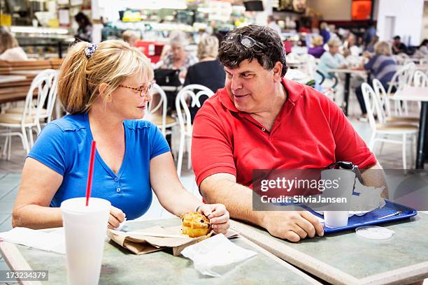 mature couple eating in mall - fat man sitting stock pictures, royalty-free photos & images