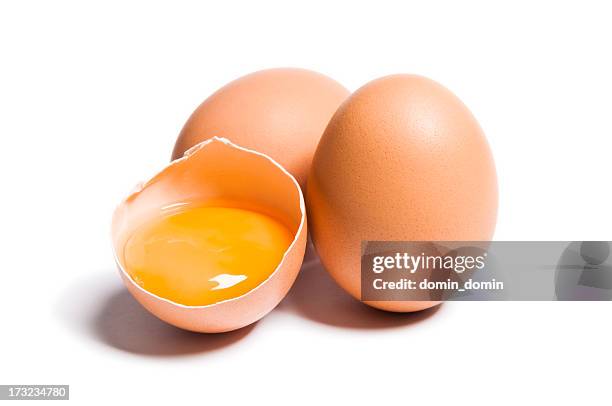 group of brown raw eggs, one is broken, isolated white - ei stockfoto's en -beelden