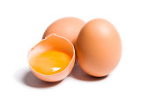 Group of brown raw eggs, one is broken, isolated white