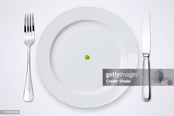 one green pea on plate. table setting with clipping path. - luxury restaurant table stock pictures, royalty-free photos & images