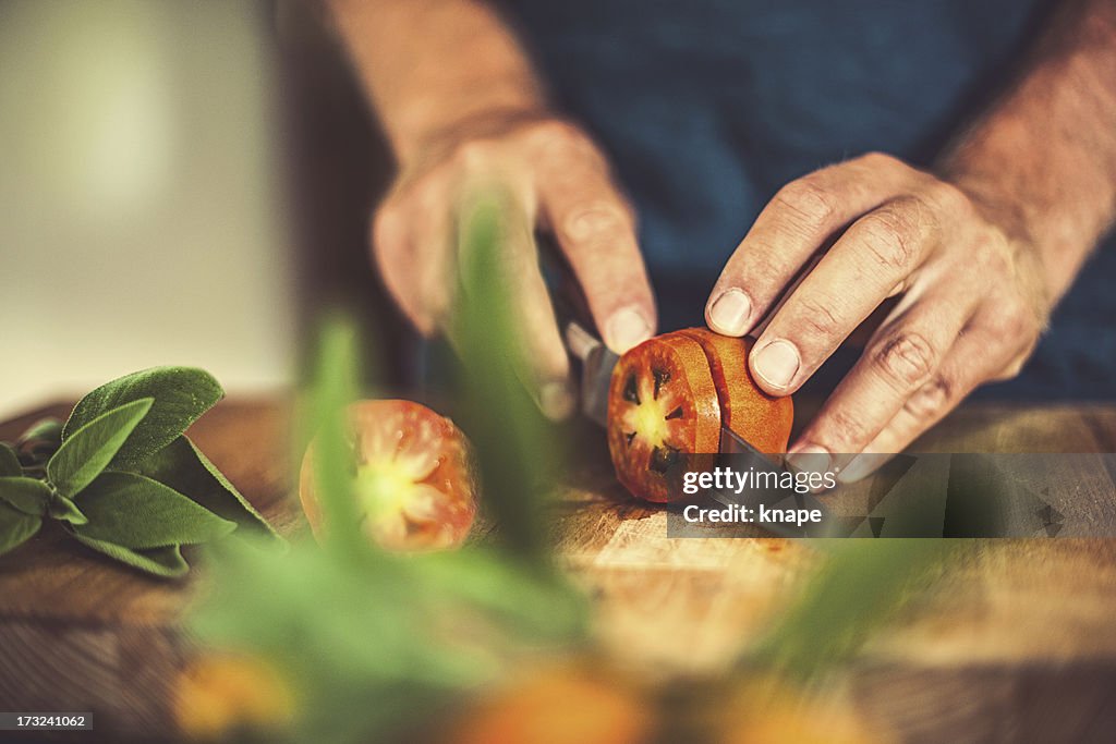 Man cutting tomatoes in rustic kitchen