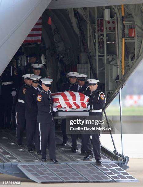 The body of Christopher MacKenzie is carried from a C-130 transport plane as two of the nineteen firefighters killed fighting the Yarnell Fire in...