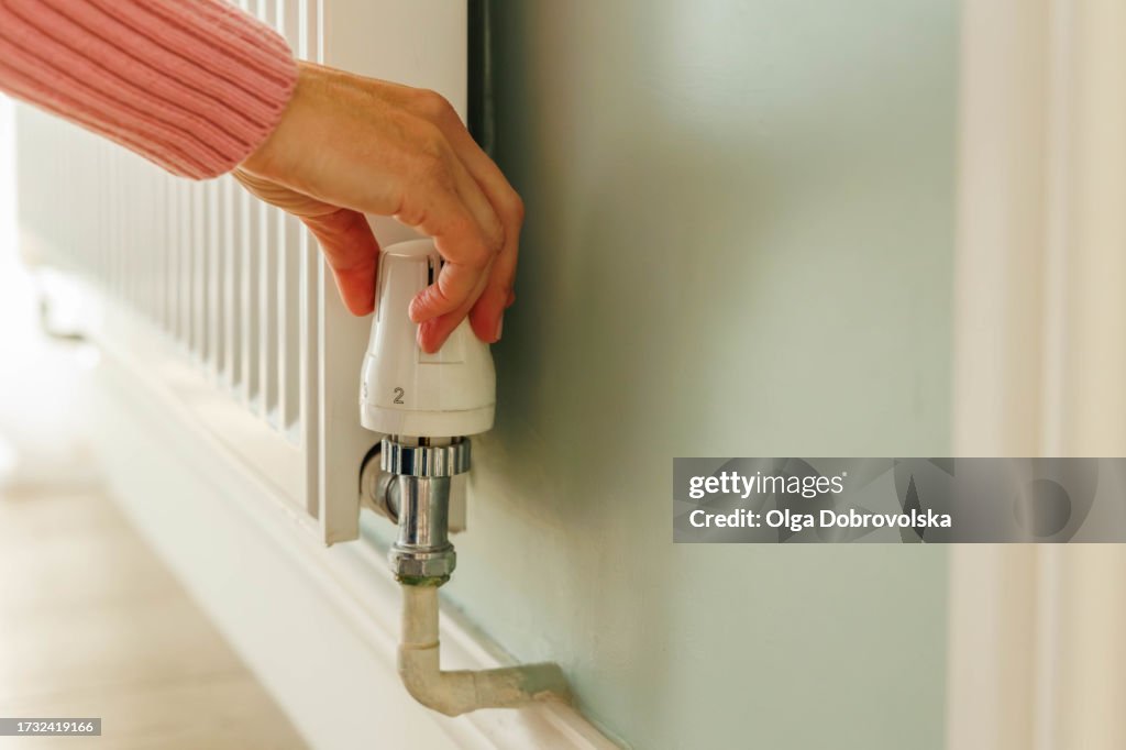 A woman's hand adjusting temperature on a heating radiator