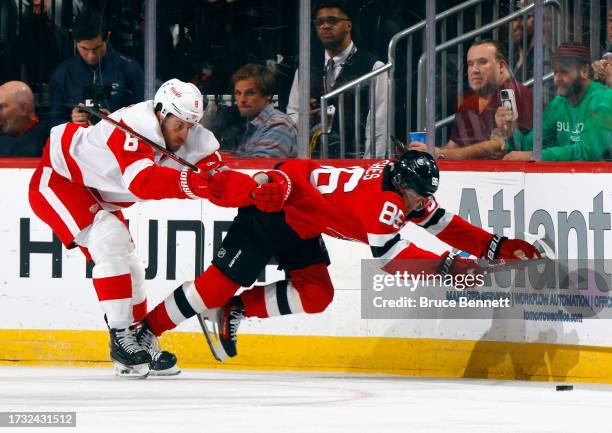 Jack Hughes of the New Jersey Devils is checked by Ben Chiarot of the Detroit Red Wings during the first period at the Prudential Center on October...