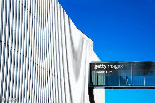 homme passant à travers une passerelle aérienne au bâtiment futuriste - passerelle pont photos et images de collection