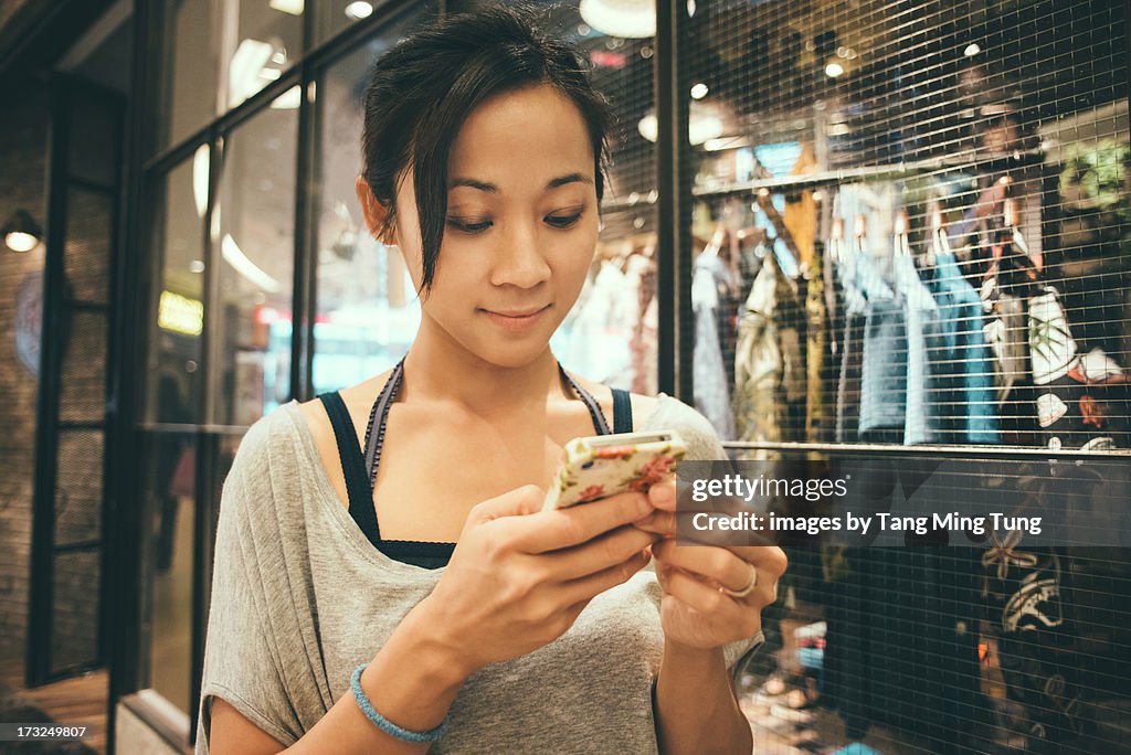 Young lady using smartphone in boutique.