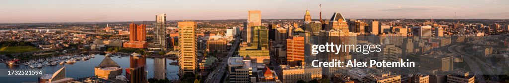 Contrasts of harbor and Downtown District of sunny Baltimore, MD. Dawn covers business center of populous city. Stitched panoramic aerial view