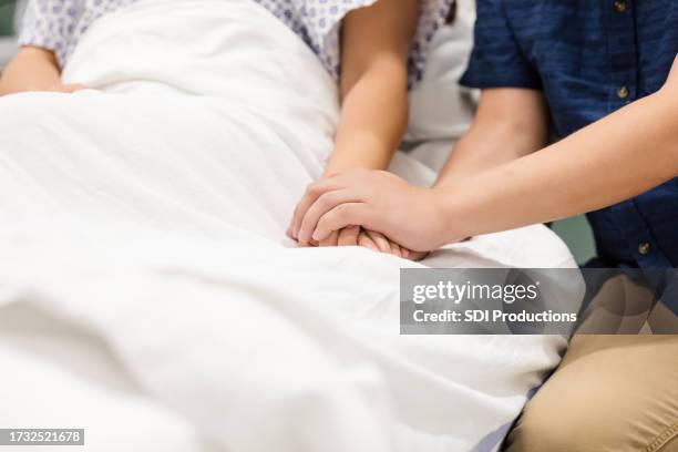 una pareja irreconocible se toma de la mano mientras está en el hospital - camilla de ruedas de hospital fotografías e imágenes de stock