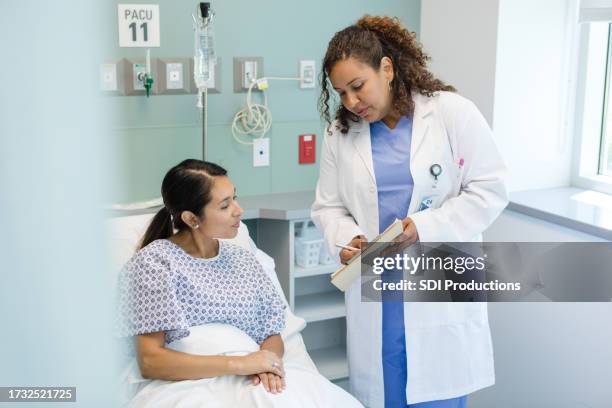 une chirurgienne demande à la patiente de vérifier les informations avant son intervention - contact avec les patients photos et images de collection