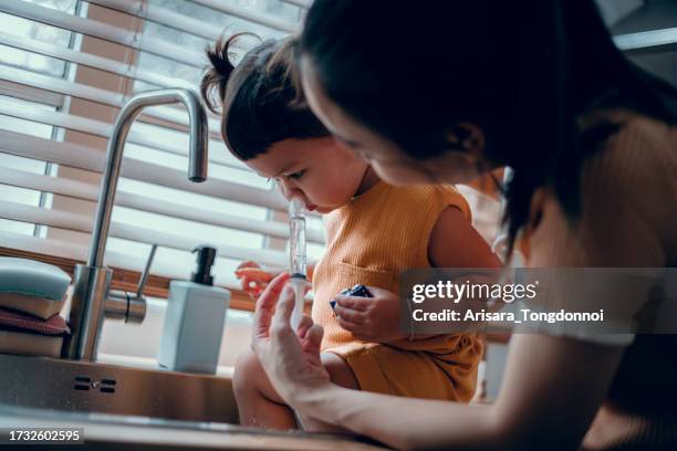mãe asiática usa soro fisiológico para enxaguar o nariz de seu filho que está resfriado. - nariz - fotografias e filmes do acervo
