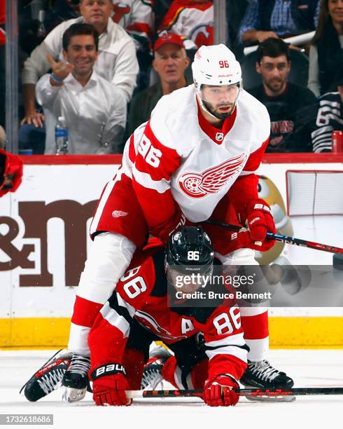 Jake Walman of the Detroit Red Wings checks Jack Hughes of the New Jersey Devils during the third period at the Prudential Center on October 12, 2023...