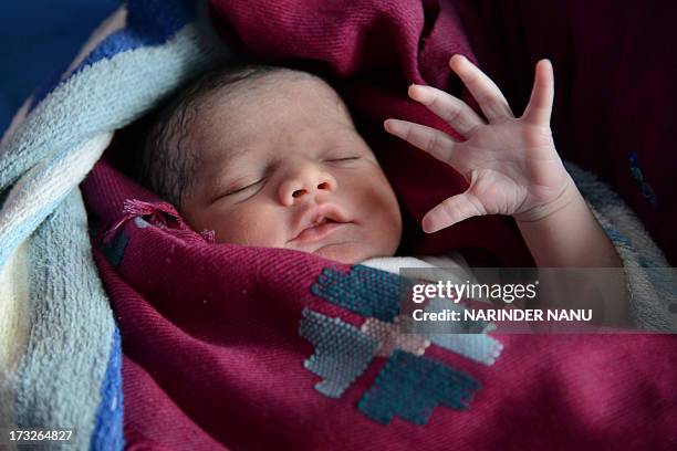 Indian mother Sonia looks on as her newborn baby girl stretches at a government hospital in Amritsar on July 11 on the occasion of World Population...