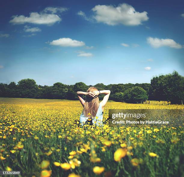 girl sitting in a field of buttercups - buttercup field stock pictures, royalty-free photos & images
