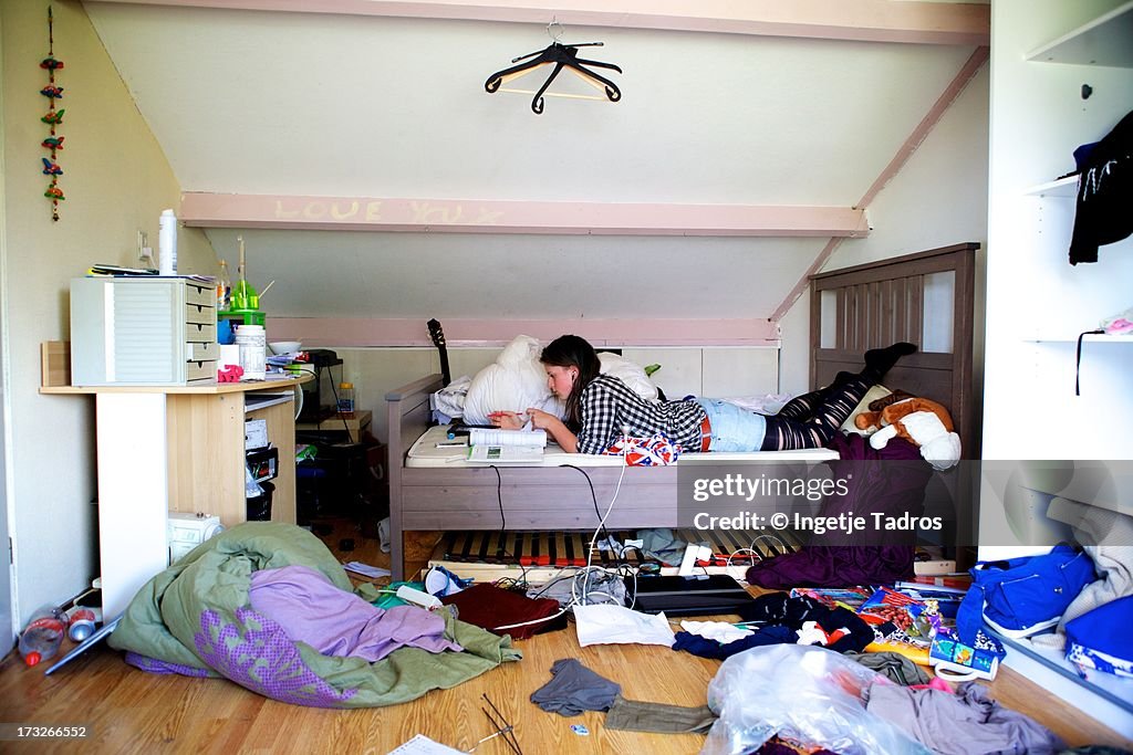 Teenager making homework in a very messy room