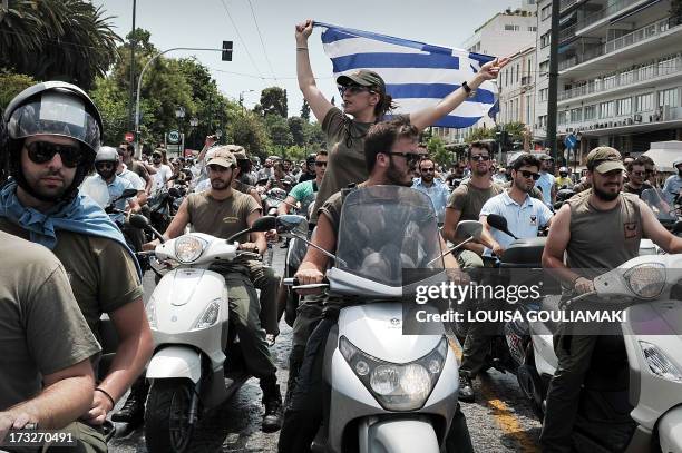 Striking municipal police display a Greek flag, while driving their motorbikes by the Greek parliament in Athens during a protest on July 11, 2013....