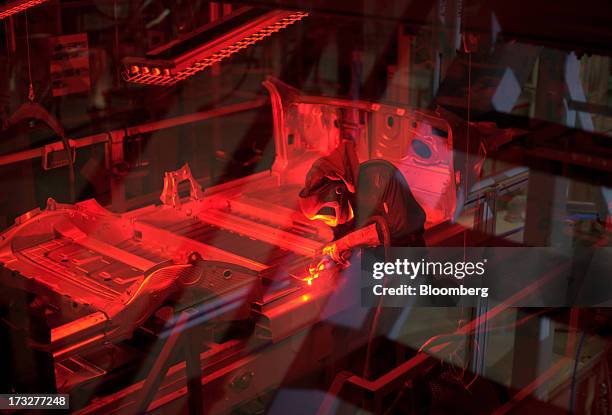 Worker welds a Model S sedan chassis at Telsa Motor Inc.'s assembly plant in Fremont, California, U.S., on Wednesday, July 10, 2013. Tesla is...