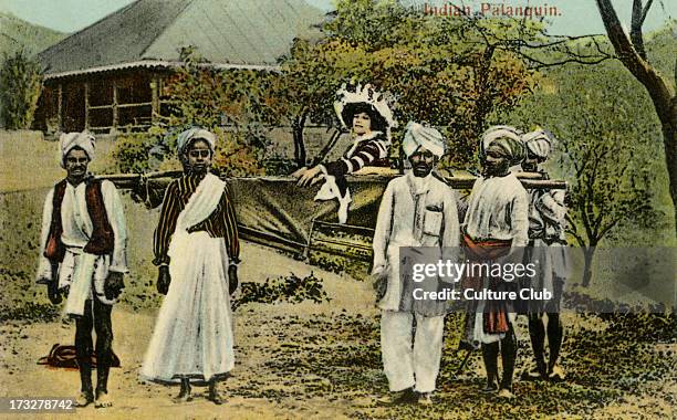 British colonial lady in Indian palanquin, flanked by attendants and servants. Colorized photograph from early 20th century. Caption reads 'Indian...