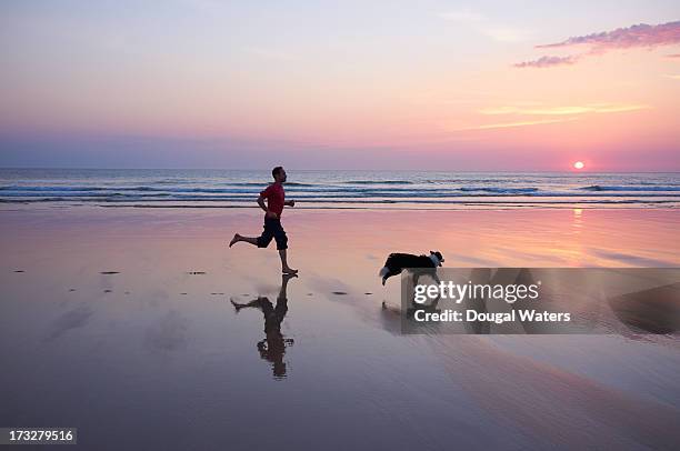 man running with dog at beach. - 犬　走る ストックフォトと画像