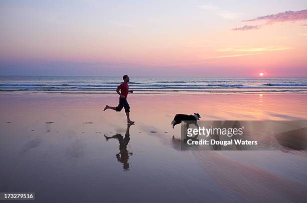 man running with dog at beach. - beach running bildbanksfoton och bilder