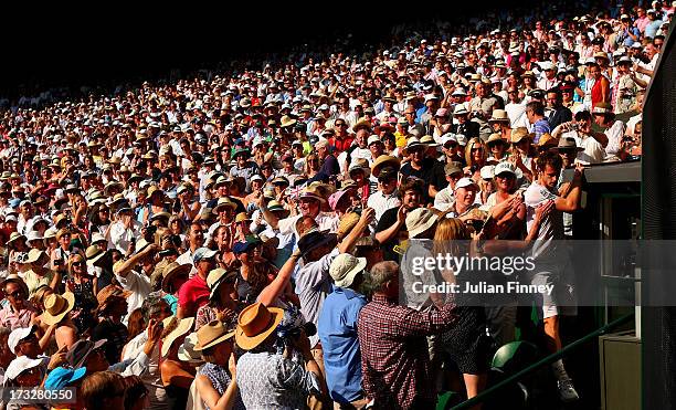 Andy Murray of Great Britain climbs down after celebrating in his player's box with friends, family and members of his coaching team following his...