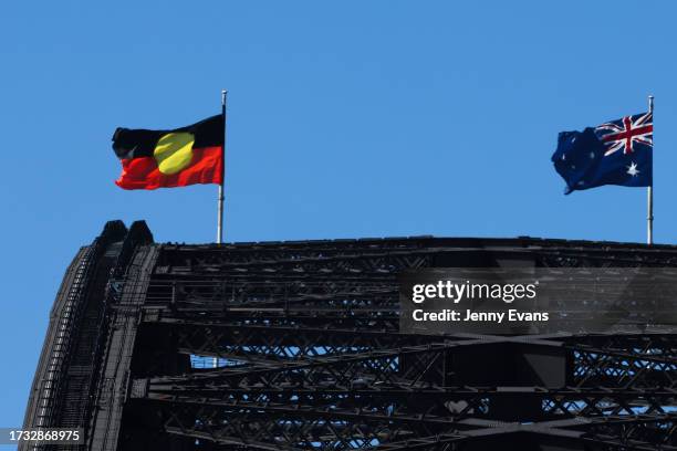 An Australian national flag and an Aboriginal flag fly from masts atop of the Sydney Harbour Bridge on October 13, 2023 in Sydney, Australia. A...