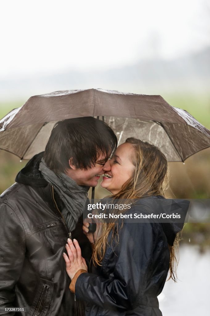 Couple kissing under umbrella in rainy day