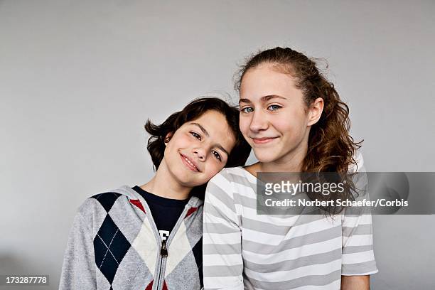 portrait of smiling brother (10-12) and sister (13-15), studio shot - girl 10 12 stock pictures, royalty-free photos & images
