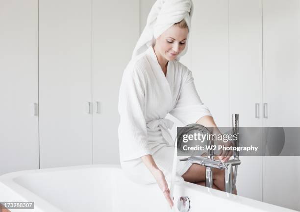 woman in bathrobe filling bathtub - filling bathtub stock pictures, royalty-free photos & images