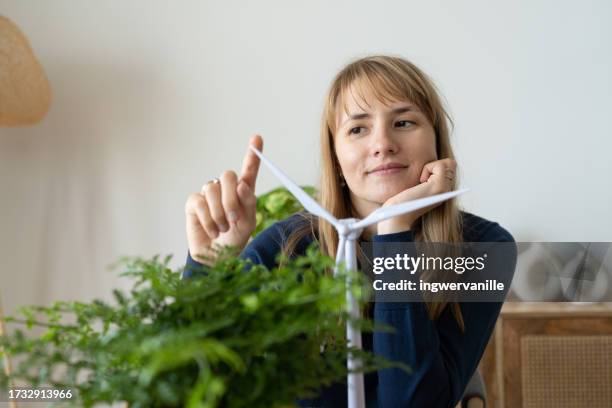 portrait of smiling freelancer with wind turbine model on desk - united arab emirates stock pictures, royalty-free photos & images