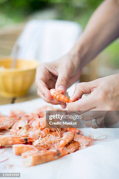 woman's hands cleaning prawns at table - garnaal vis en zeevruchten stockfoto's en -beelden
