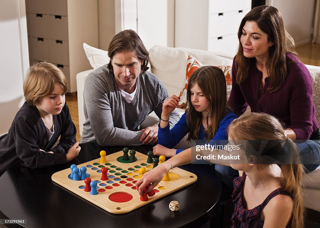 Family playing ludo together at table in living room