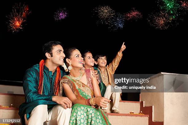 family enjoying firework display on diwali - indian girl pointing stock-fotos und bilder