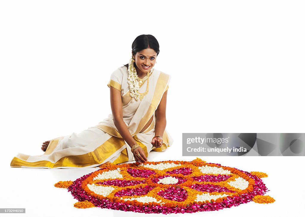 South Indian woman making a rangoli of flowers at Onam