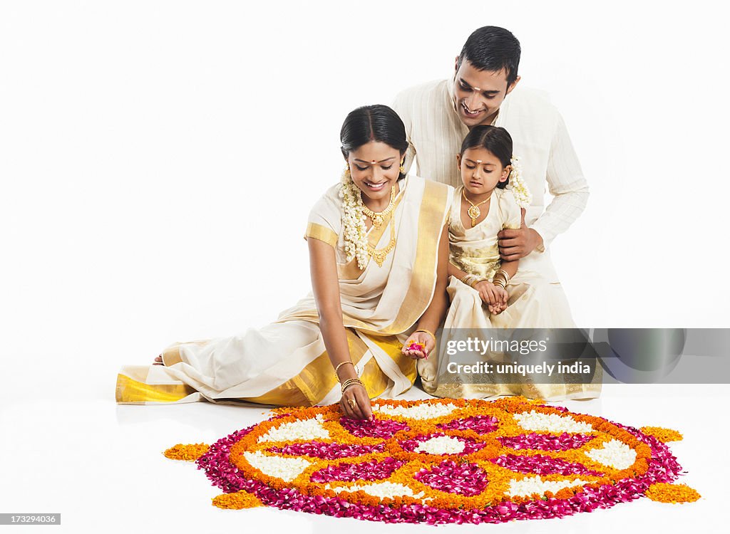 South Indian family making a rangoli of flowers at Onam