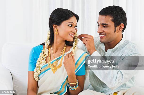 south indian man putting gajra in his wifes hair - arranging stock pictures, royalty-free photos & images