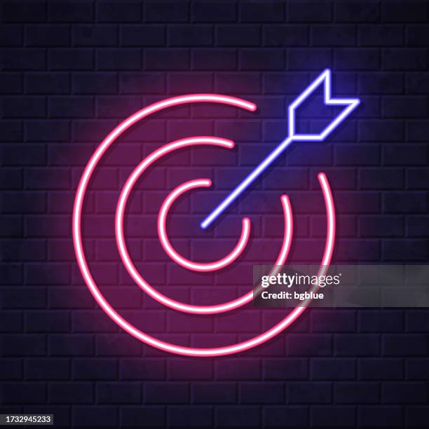 target. glowing neon icon on brick wall background - dart stock illustrations