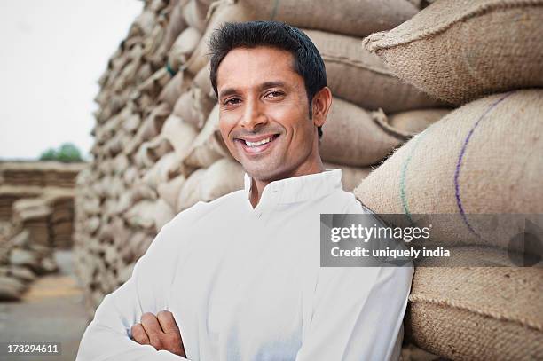 man leaning against a stack of wheat sacks, anaj mandi, sohna, gurgaon, haryana, india - kurta stock pictures, royalty-free photos & images