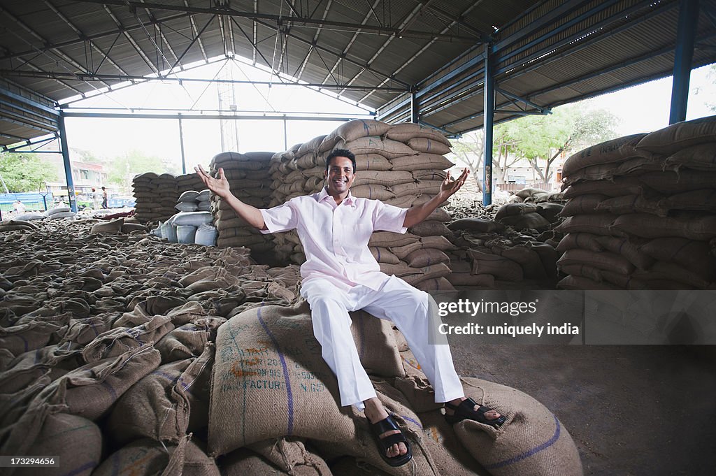 Man sitting on stack of wheat sacks in a warehouse, Anaj Mandi, Sohna, Gurgaon, Haryana, India