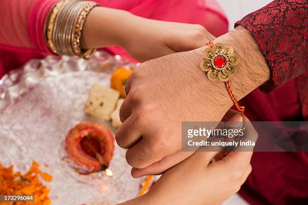 teenage girl tying rakhi on her brother wrist - akhi stock pictures, royalty-free photos & images