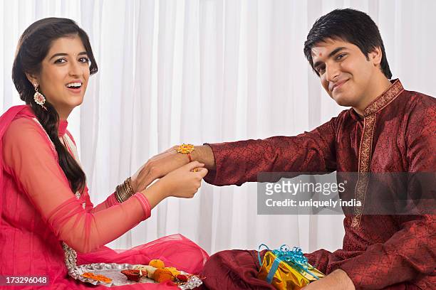 teenage girl tying rakhi on her brother wrist - rakhi ストックフォトと画像