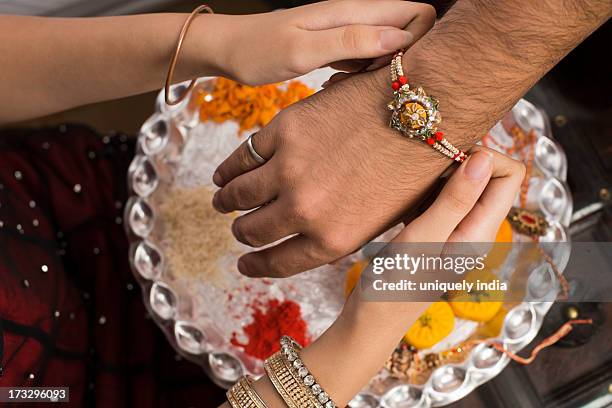 sister tying rakhi on her brother wrist - raksha bandhan fotografías e imágenes de stock