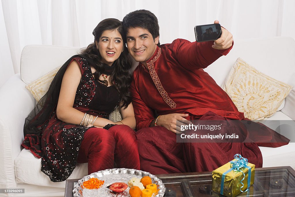 Brother and sister taking a picture of themselves with a mobile phone at Raksha Bandhan