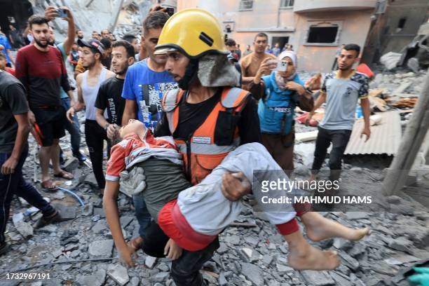 Graphic content / Palestinian civil defence members and others carry a child killed in an Israeli bombardment from a building in Khan Yunis on the...