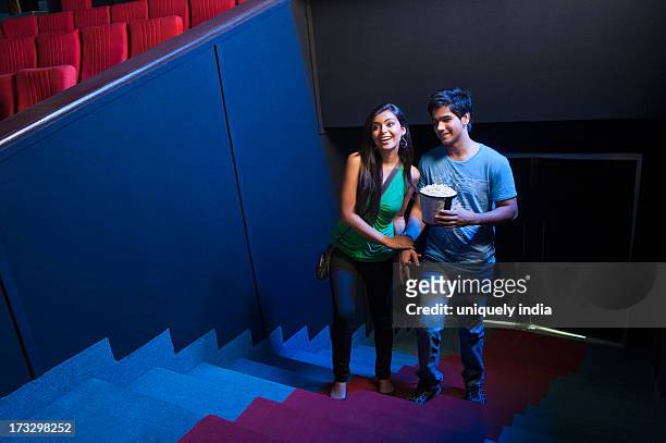couple moving up on steps in a cinema hall - indian couple in theaters stock pictures, royalty-free photos & images