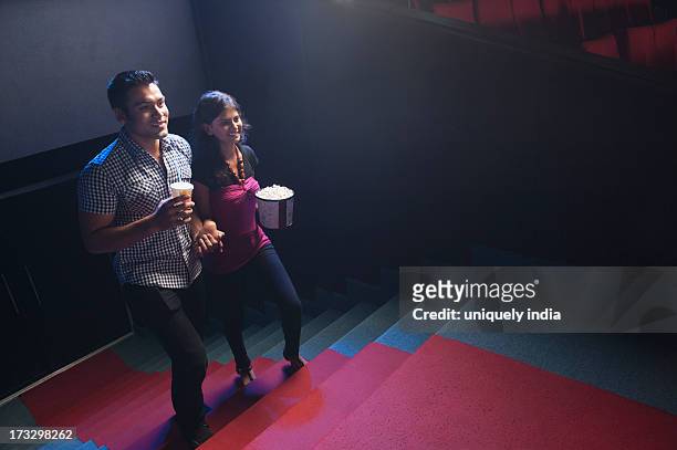 couple moving up on steps in a cinema hall - indian couple in theaters - fotografias e filmes do acervo