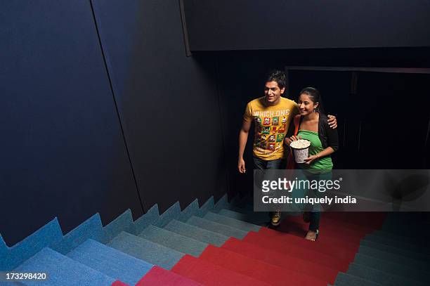 couple moving up on steps in a cinema hall - couple entering the theater stock pictures, royalty-free photos & images